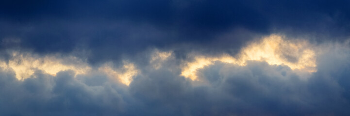 Dark storm clouds illuminated by the bright evening sun, panorama