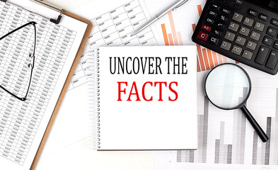 UNCOVER THE FACTS text on notebook with clipboard and calculator on a chart background