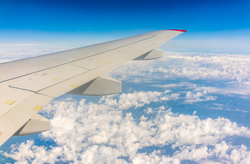 View from the airplane window at a beautiful cloudy sky and the airplane wing