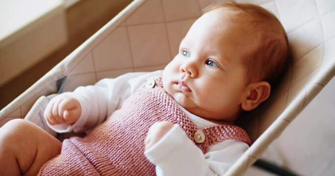 Little baby girl lies on a swing or deck chair and rides. child portrait. High quality 4k footage