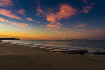 The colours of the sunrise reflected in the sky above one of Papagayo's beaches in Lanzarote