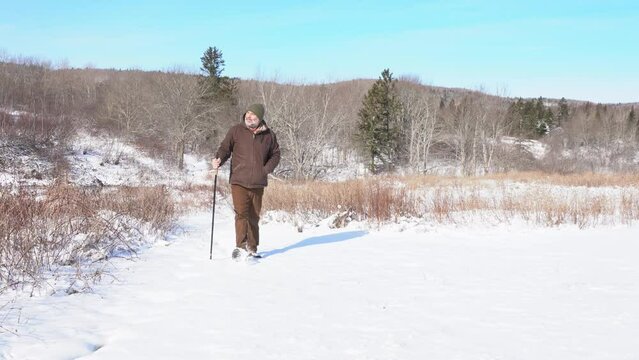 A man experiencing knee and leg pain during a winter's walk in the countryside.