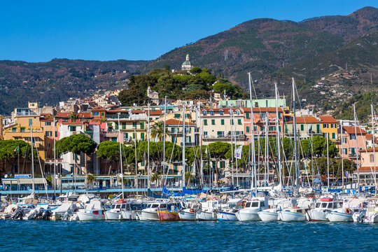 Sanremo, Italy, day view from the sea with boats and yachts to the old town of Sanremo (La Pigna) and Madonna della Costa Church on the hilltop, Liguria, Italy