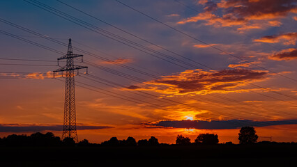 Beautiful sunset with a dramatic sky and overland high voltage lines near Tabertshausen, Bavaria, Germany