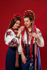 Ukrainian women in traditional ethnic clothing and floral red wreath on viva magenta studio background. National embroidered dress call vyshyvanka. Pray for Ukraine