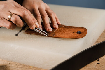 Process of creation genuine leather product. Craftsman is cutting genuine leather using cutter...