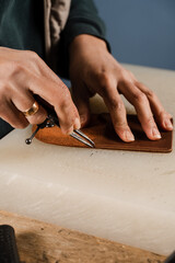 Process of creation genuine leather product. Craftsman is cutting genuine leather using cutter knife for creation natural leather products. Equipment for genuine leather production in workshop.