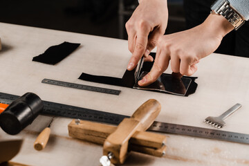 Craftsman is cutting genuine leather using cutter knife for creation natural leather products....