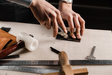 Craftsman is cutting genuine leather using cutter knife for creation natural leather products....