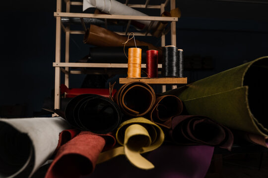 Rolls of natural leather and needle and spools of thread in a craftsman workshop. Handmade genuine leather production in the factory.