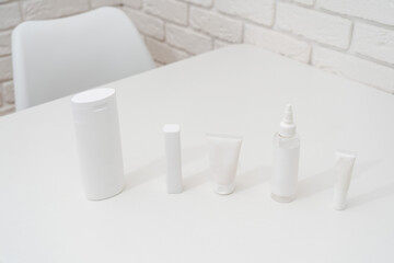 Packing tubes on table and white brick wall background. Cosmetics, beauty and spa concept