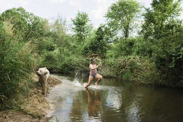 Girl running in lake with Labradoodle by lakeshore amidst forest