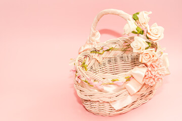 Empty easter basket decorated flowers and ribbon with pink background