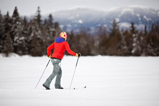 A young woman skiis across snowcovered Reddington Pond in the mountains of western Maine.