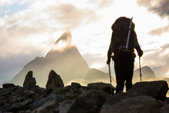 Backpacker approaches dramatic mountain summit, Canada.