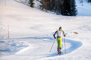 Cross-country skier practising classic technique on a ski trail in the Alps on a sunny winter day