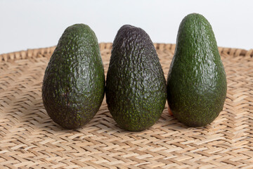 Whole avocados on wicker sieve