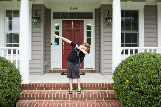 Tween Boy Dabs on Front Porch of His House, Standing on Brick Steps