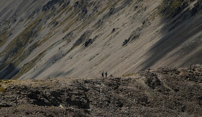 Two active hikers walking on exposed mountain ridge path trail in Nelson Lakes National Park Southern Alps New Zealand