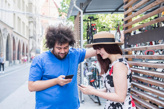 Young couple text messaging on mobile phone in city