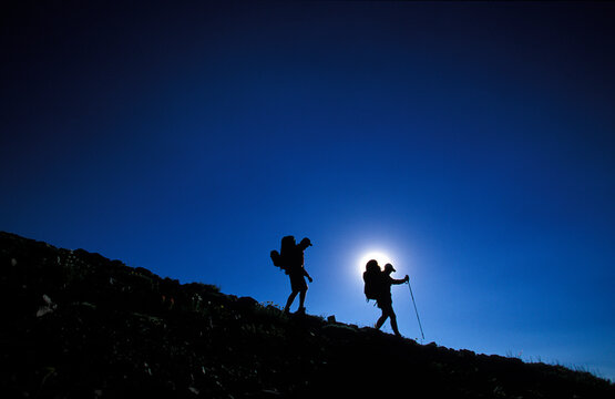 Man and woman hike / backpack down hill on a mountain ridge Kirkwood, California