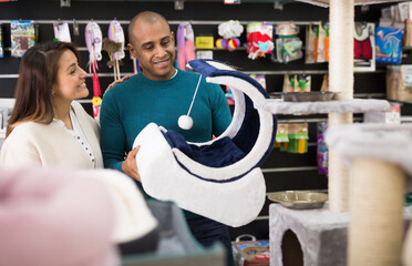 Woman and man choosing different accessories for their pets in a pet store