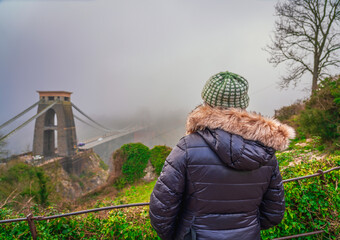 Woman looking at famous Clifton bridge in Bristol England on a foggy day