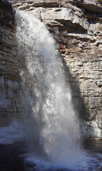 Sideview of a powerful waterfall during winter time with a stone background