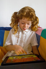Bambina bionda con riccioli e trecce, che gioca con un tablet e sidi verte