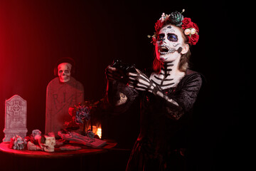 Santa muerte model using controller to play video games in studio, playing gaming competition and...