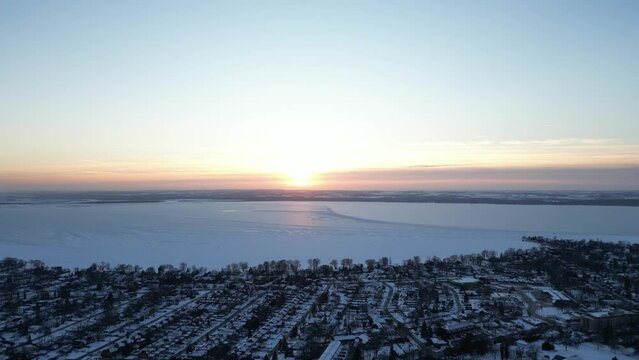 Drone flying towards Lake simcoe during winter and golden hour  sunset