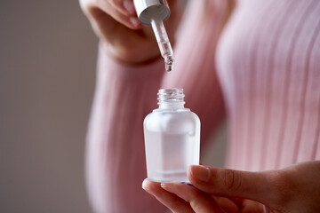 Woman holding a bottle of aromatherapy essential oil and dropping a drop