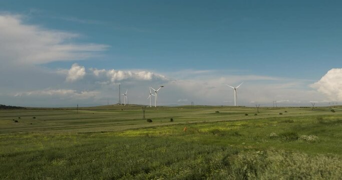 Wind generator farm in green fields in Gori below blue skies, Georgia.