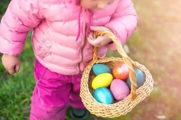 Fototapeta na wymiar child collects colorful Easter eggs in basket. Easter egg hunt concept