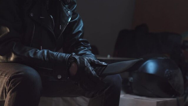 Person wearing black leather gloves takes out huge knife from a duffle bag