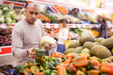 Portrait of man in produce section of supermarket choosing sweet paper and bananas
