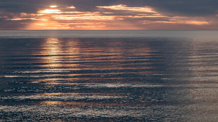 Fototapeta premium A vivid gold and orange sunset reflects across Lake Michigan. 