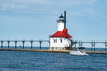 Fototapeta na wymiar A boat heads out next to the pier of the St. Joseph north pier lighthouse on Lake Michigan.