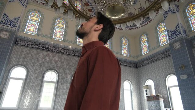 A young bearded man standing watching the ceiling of the mosque, Muslims who go to historical and holy places pray
