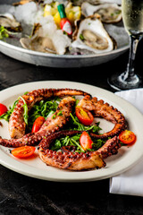 Grilled octopus. Prepared in traditional Italian style: fried in olive  oil, garlic and seasoned with salt and pepper. Served over bed of arugula salad, cherry tomatoes and seasoned with fresh herbs.