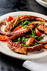 Grilled octopus. Prepared in traditional Italian style: fried in olive  oil, garlic and seasoned with salt and pepper. Served over bed of arugula salad, cherry tomatoes and seasoned with fresh herbs.