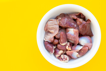 Mixed chicken entrails in white bowl on yellow background.