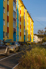 View of colorful multi-colored residential buildings. Cars are parked near the buildings. Palatka urban-type settlement, Magadan region, Far East of Russia.