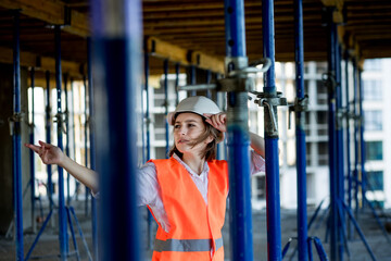 Confident Female builder checks fastenings on a monolithic structure. Construction concept