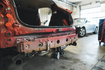 Medium shot of a red car body in a repair shop. High quality photo