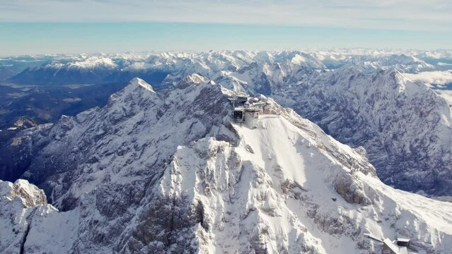 aerial orbiting around the summit of zugspitze a snowy mountain peak in the alps with an impressive building on top