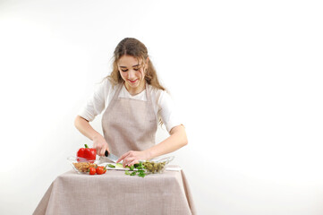 woman preparing eating salad at table with organic vegetables, enjoying healthy diet, standing in light kitchen interior. Lady cooked veggie meal at home. Weight loss concept. High quality photo