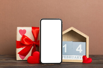 mobile phone with blank screen on colored background with hearts, calendar and gift box, valentine day 14 february concept perspertive view flat lay