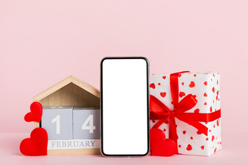 mobile phone with blank screen on colored background with hearts, calendar and gift box, valentine day 14 february concept perspertive view flat lay
