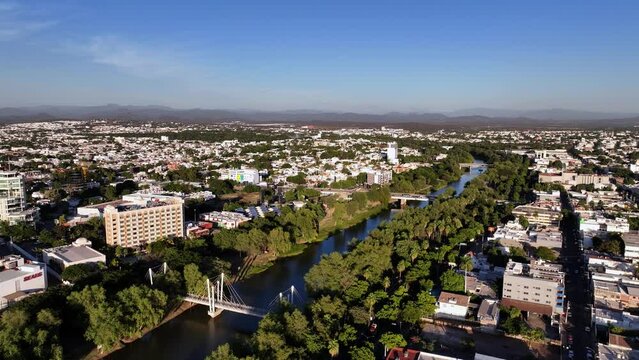 Aerial overview of R&iacute;o Tamazula river and the cityscape of Culiacan city, golden hour in Sinaloa, Mexico